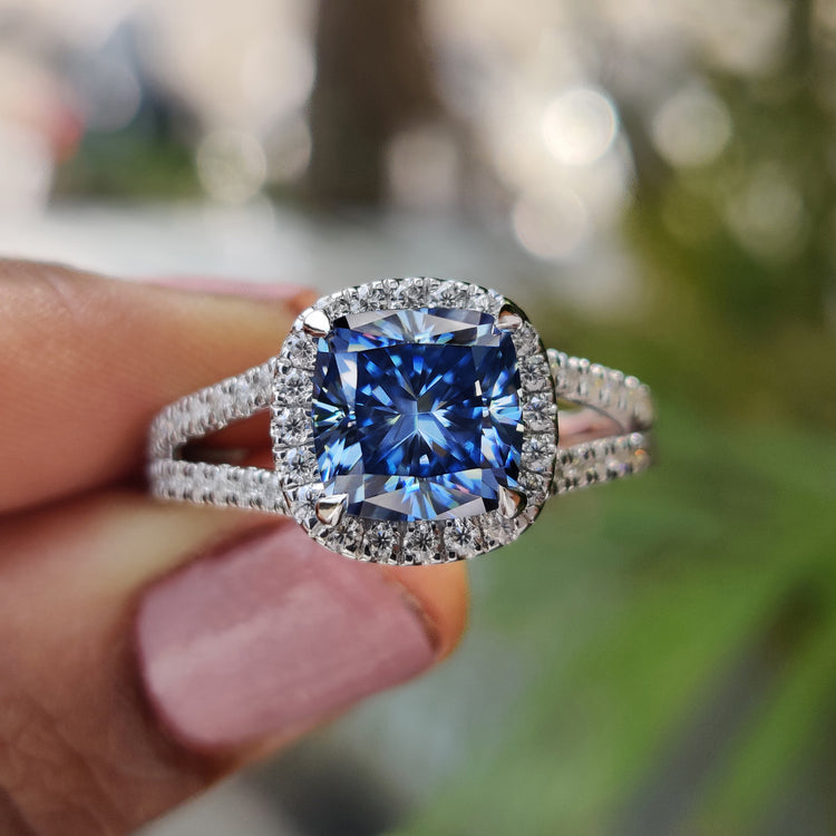 Royal dark blue cushion cut moissanite ring with white gold halo and split shank band.