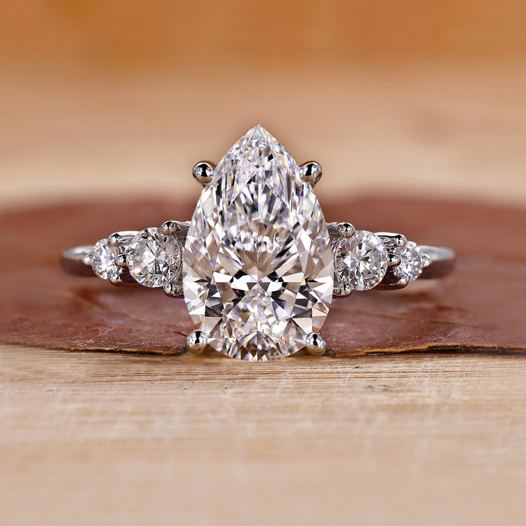 Pear cut diamond engagement ring with five round side stones.