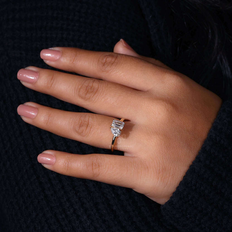 2 stone engagement ring featuring a toi et moi design with emerald and pear cut diamonds in a claw prong setting.