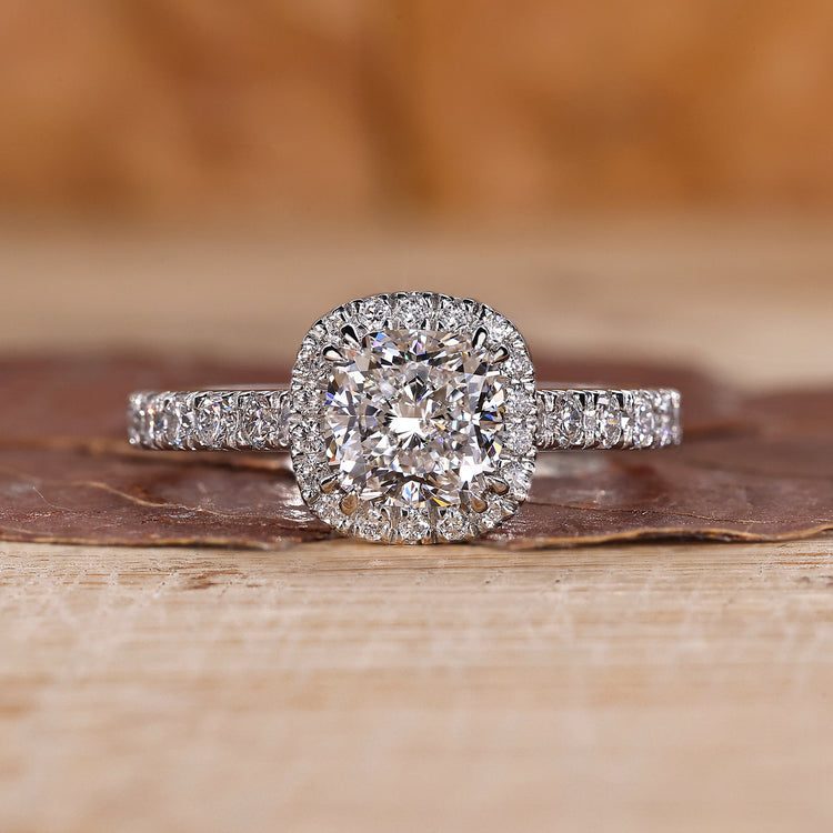 Cushion cut halo diamond ring with pave setting details.