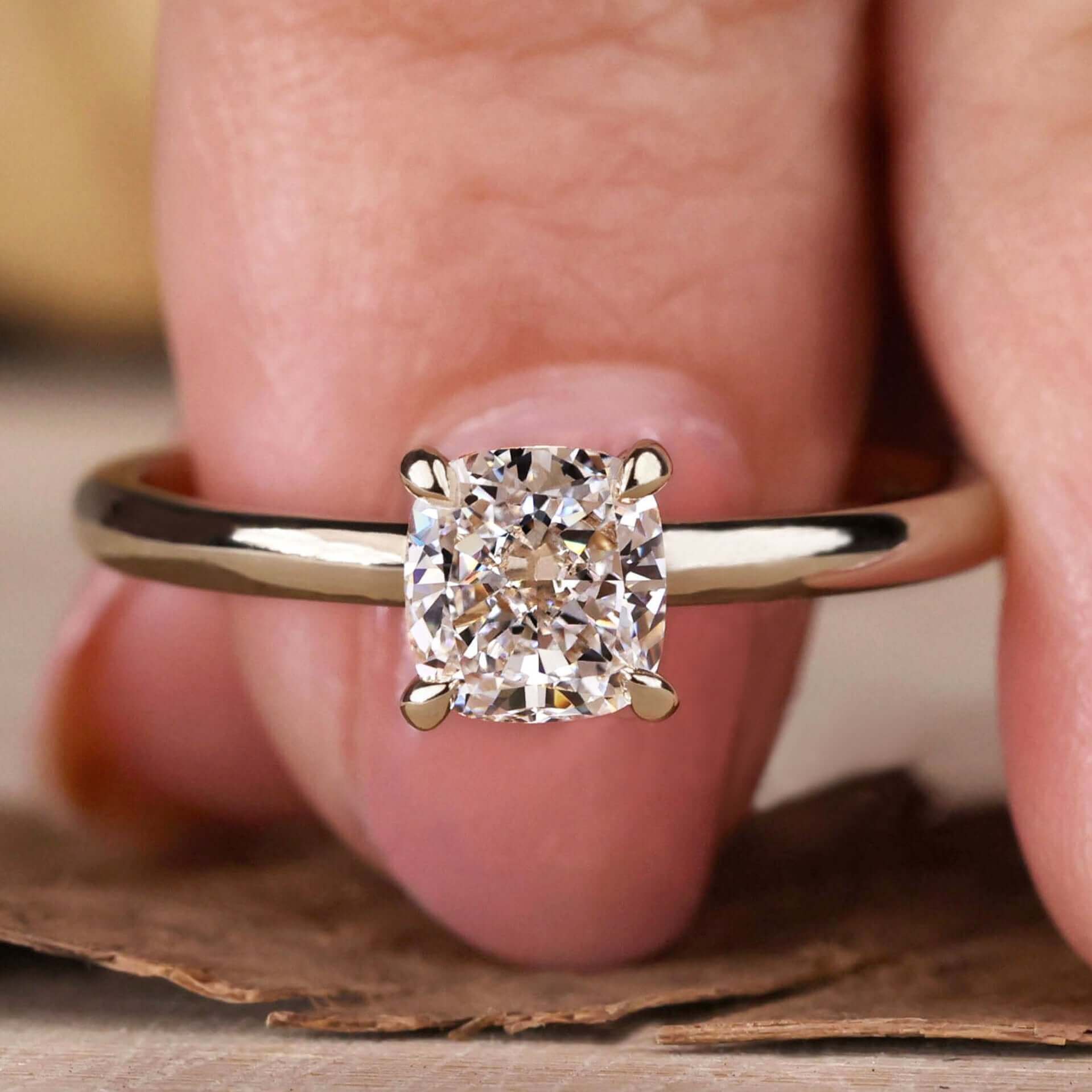 Gold engagement ring with a cushion cut diamond in a 4 prong claw setting for a timeless and elegant design.