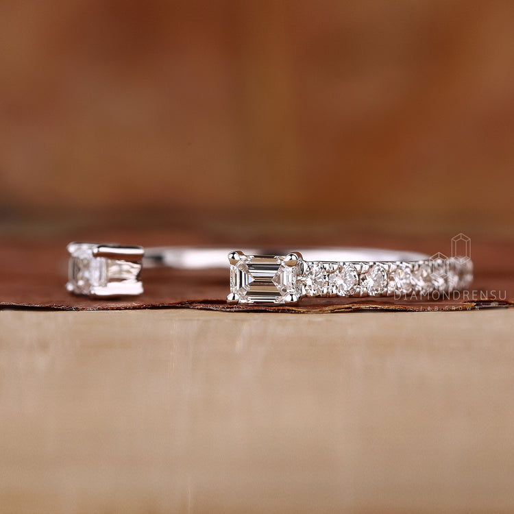 Handmade white gold wedding band with emerald and round stones