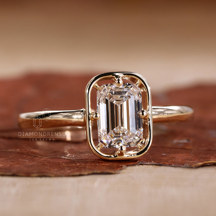 Solitaire diamond ring features one emerald cut diamond.