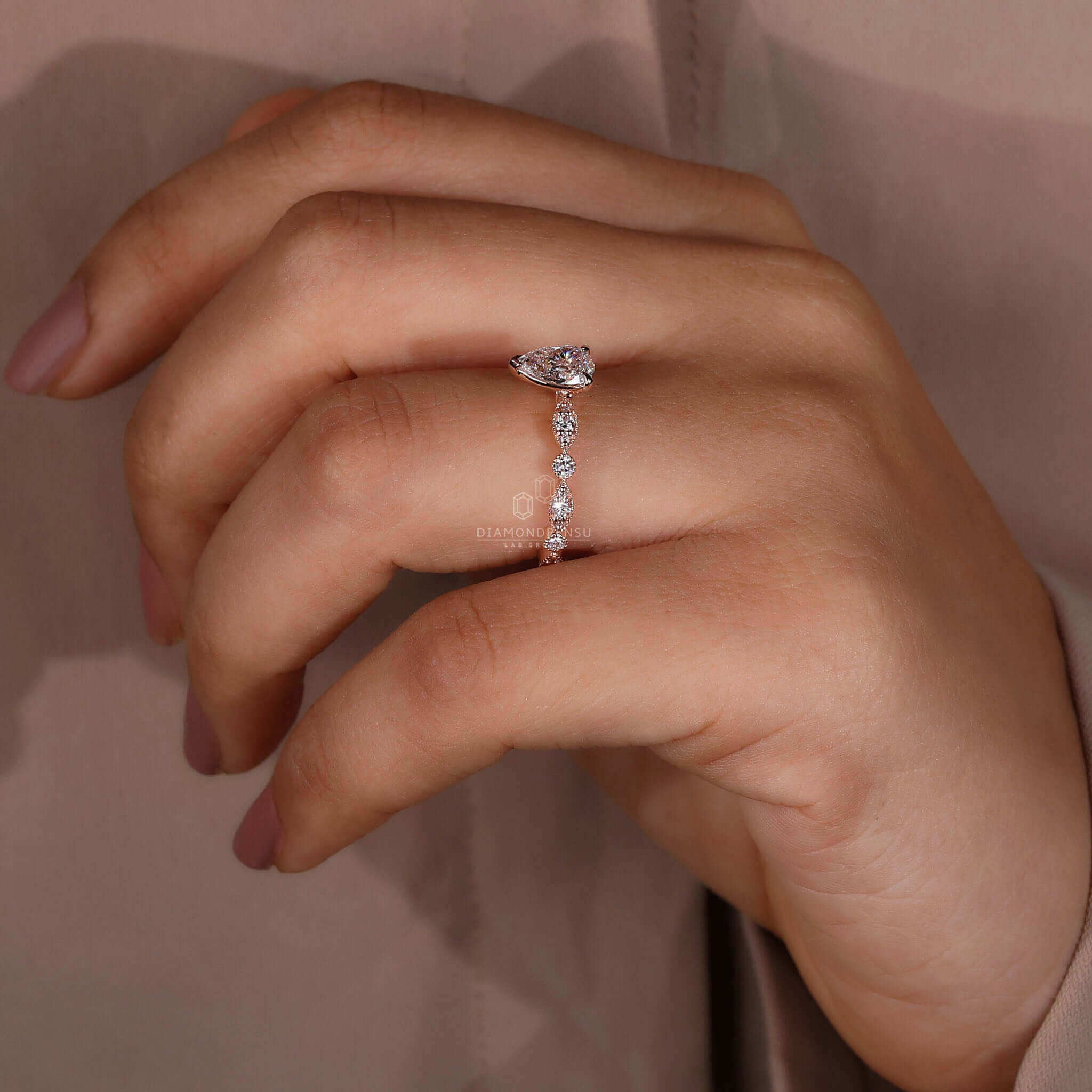Round diamond engagement ring in rose gold, crafted with pear shaped ring diamond accents.