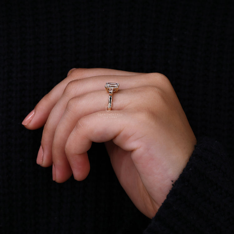 Proposal engagement ring with emerald cut centre and tapered side diamonds.