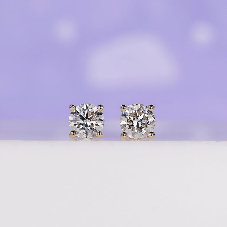 Round diamond stud earrings crafted in yellow gold with prong settings.