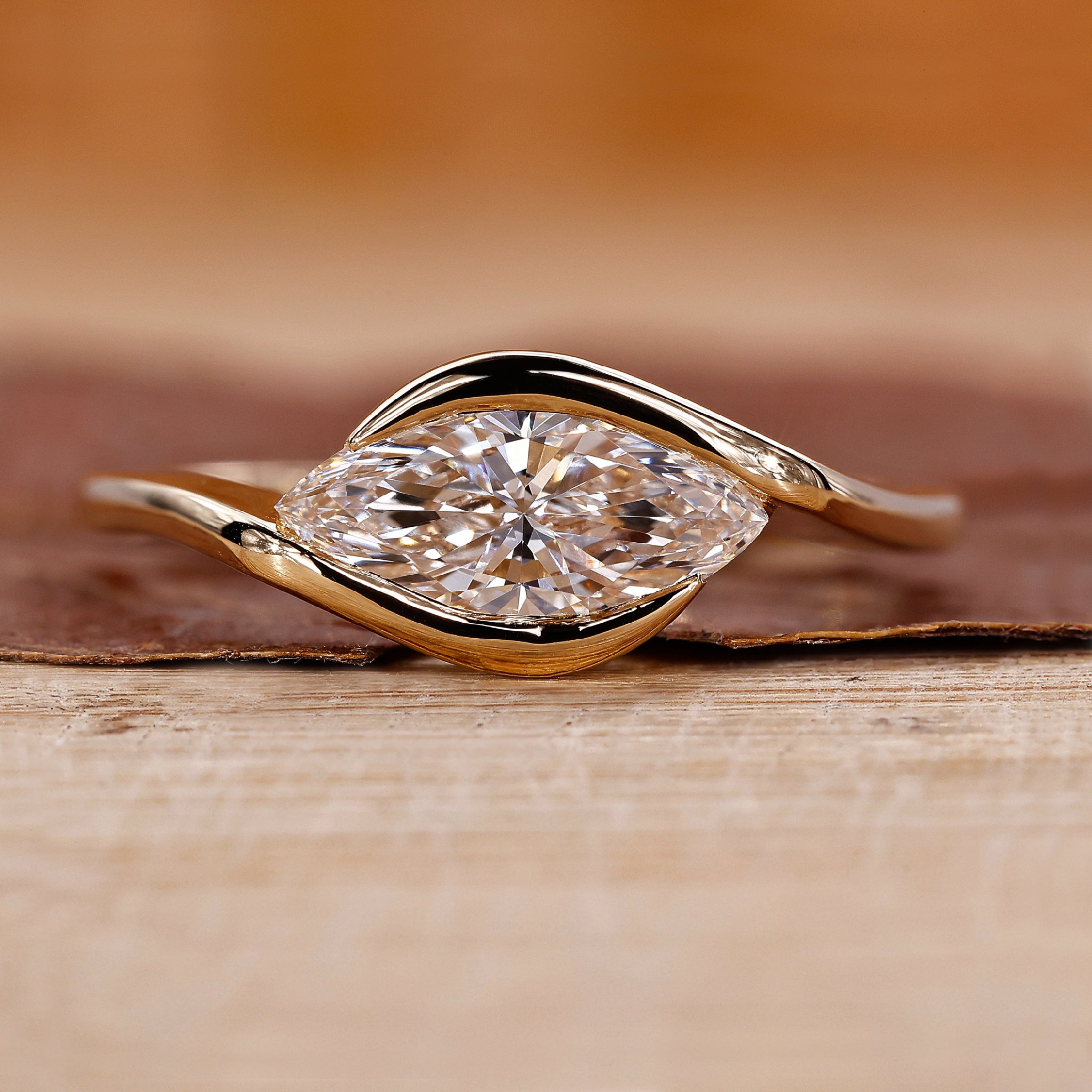 East west engagement ring featuring a marquise diamond in yellow gold.