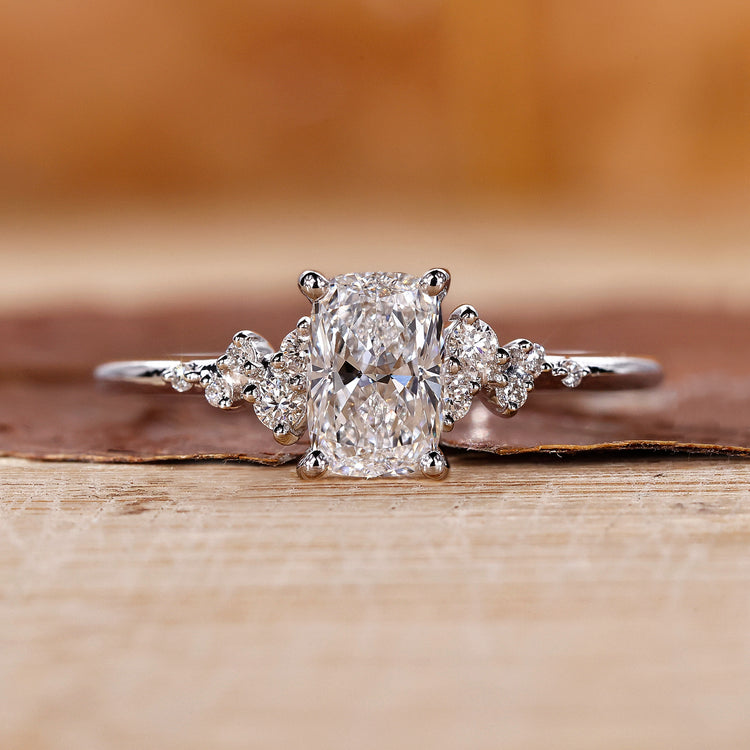 Elongated cushion ring with round side stones in white gold.