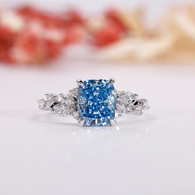 Blue diamond engagement ring with cushion cut centre in white gold.