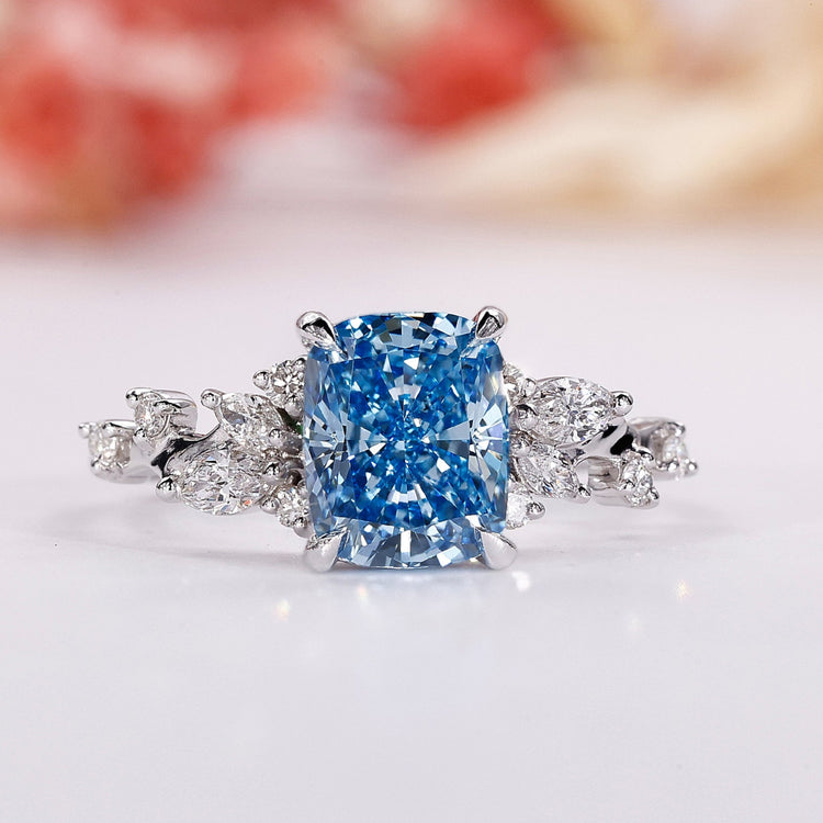 Blue diamond engagement ring with cushion cut centre in white gold.