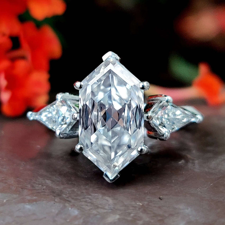 Elongated hexagon engagement ring with kite cut side stones in a white gold setting.