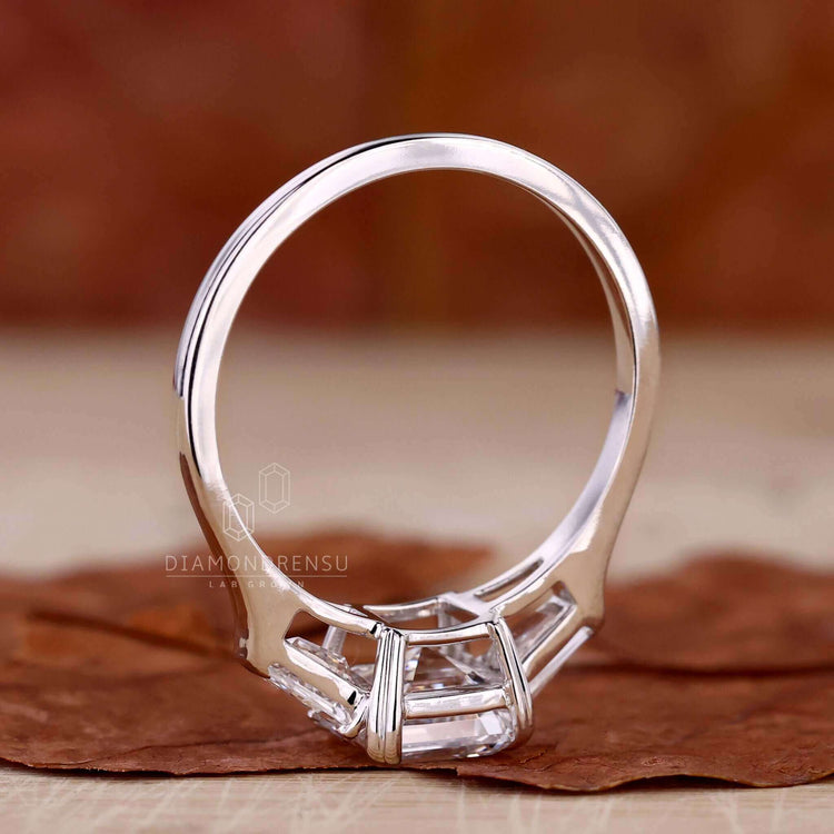 Three stone diamond ring with a stunning asscher cut centre stone and claw prong engagement ring style.