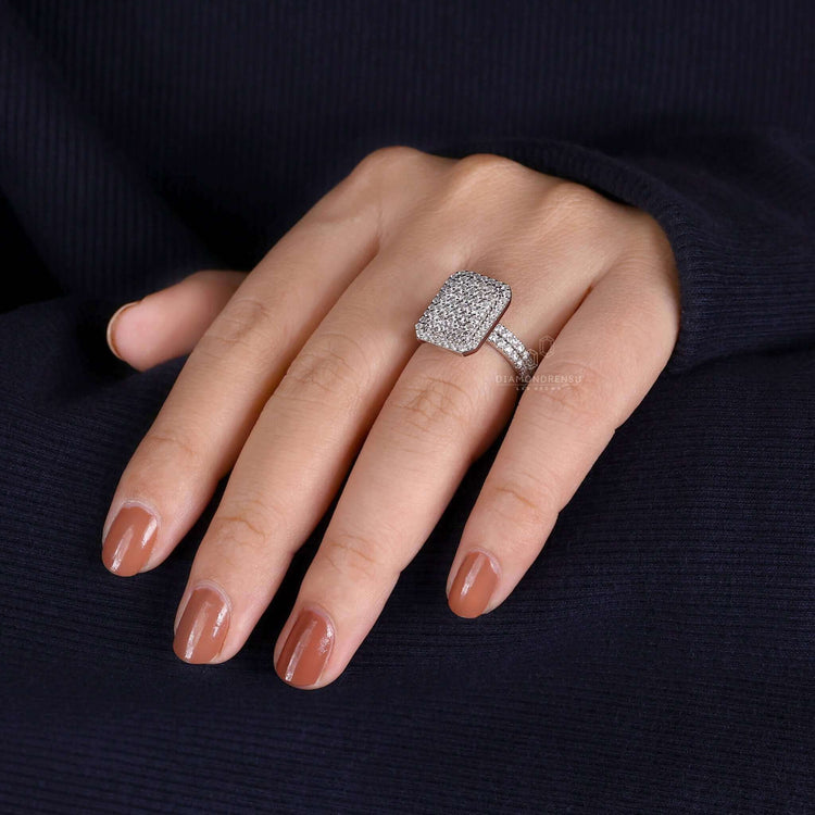 A close-up photo of a polished platinum engagement ring featuring a round diamond in a cluster setting, with a focus on the intricate details of the setting.