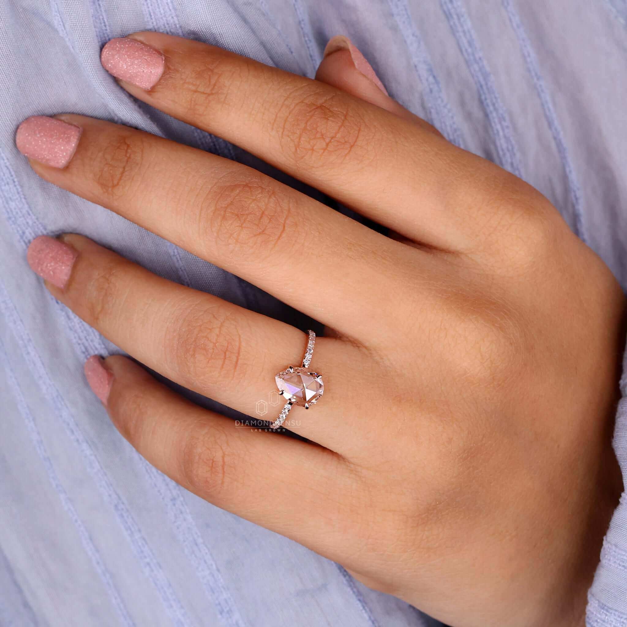 Engagement ring with pave accents and a pear shaped diamond ring centre stone in rose gold.