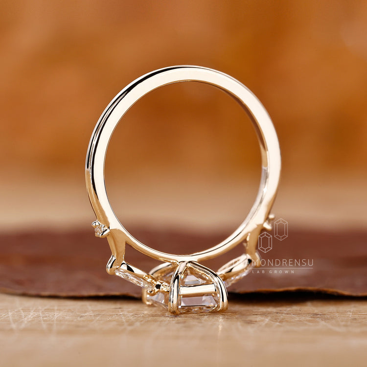 Proposal ring with emerald center diamond and prong set side stones.