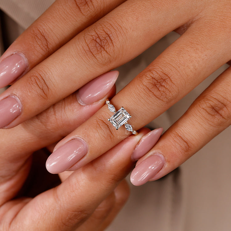 Custom engagement ring with 4 claw prong set emerald center and side stones.