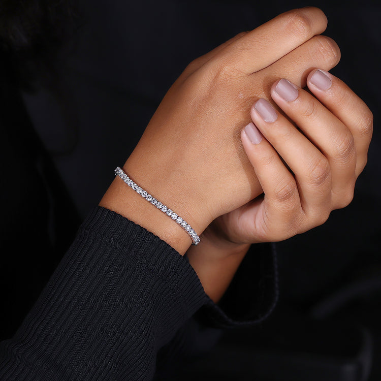 Gold tennis bracelet featuring round diamonds and custom handmade detail.