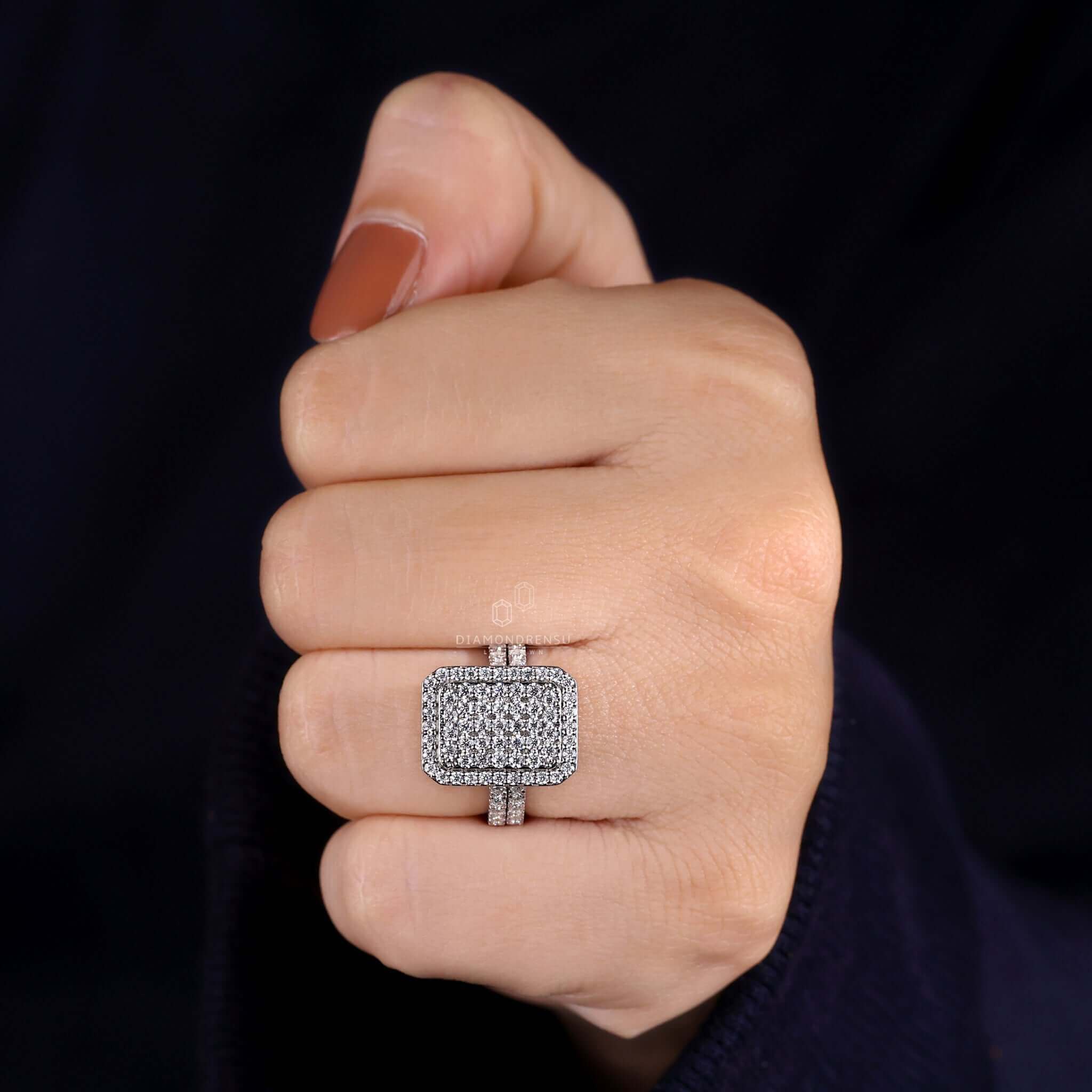 A smiling woman admiring a sparkling round diamond engagement ring with a cluster setting on her left hand.
