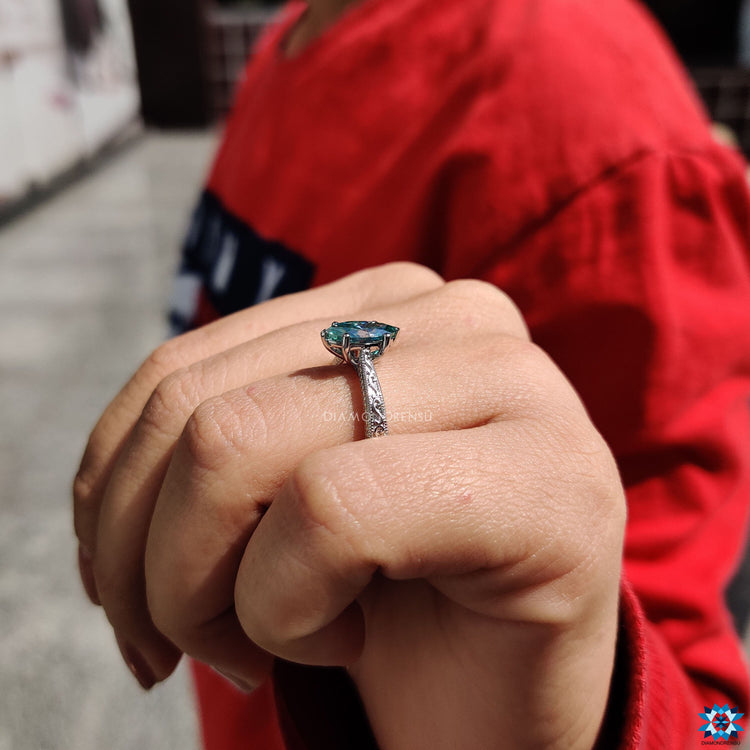 Elegant solitaire marquise ring featuring cyan blue moissanite and vintage milgrain.