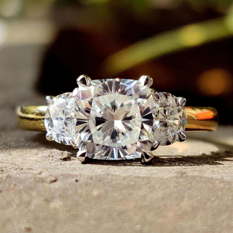 3 stone cushion cut engagement ring with half moon side stones.