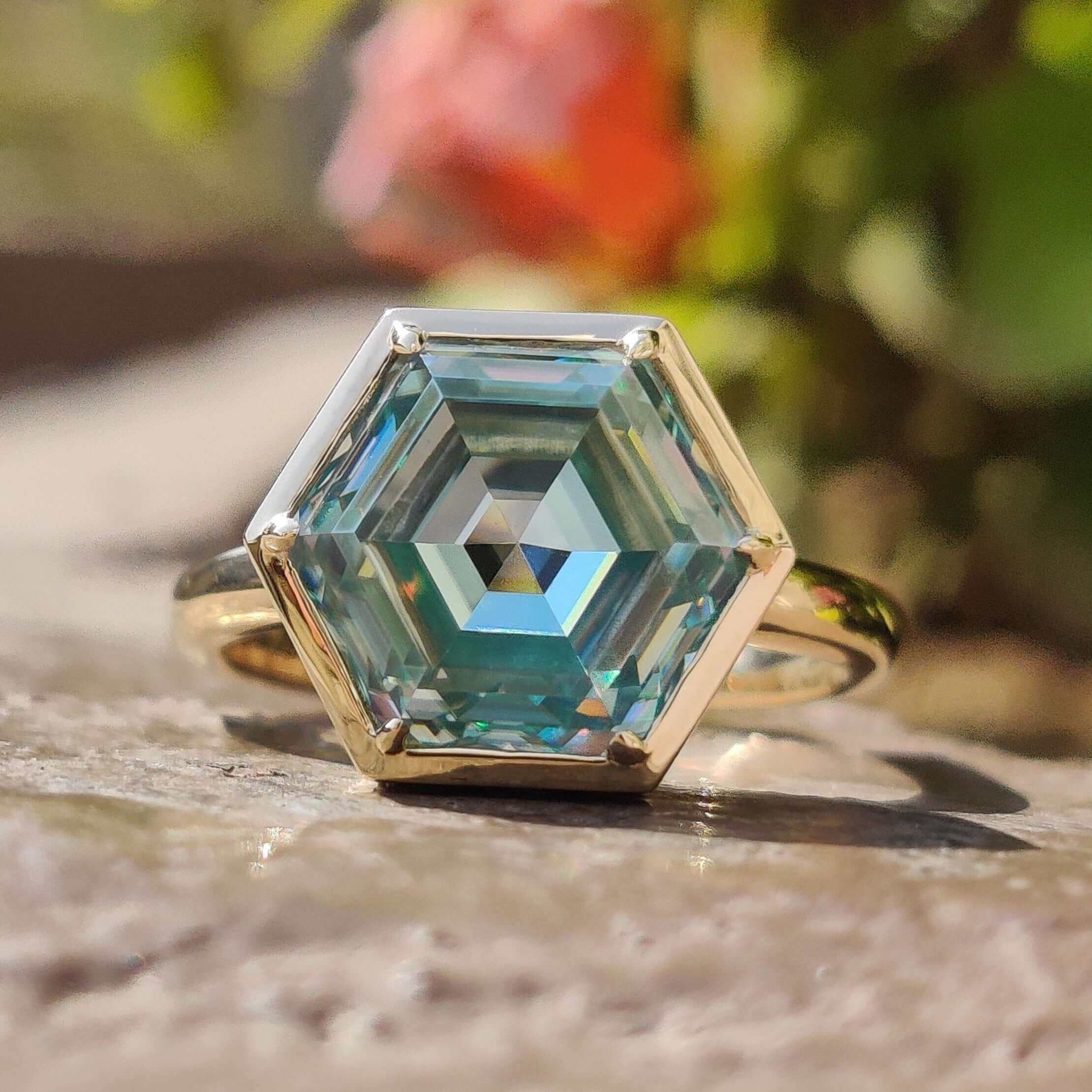 Yellow gold bezel solitaire engagement ring with hexagon cut cyan blue moissanite.