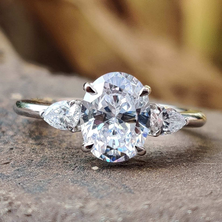 Oval center moissanite ring with two pear side stones.