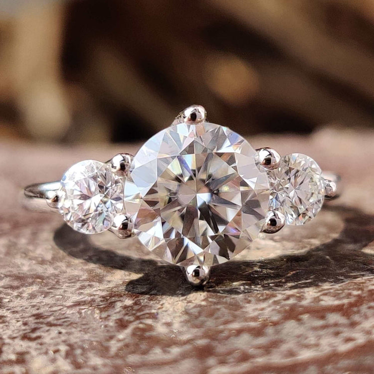 Round cut moissanite three stone engagement ring in white gold.