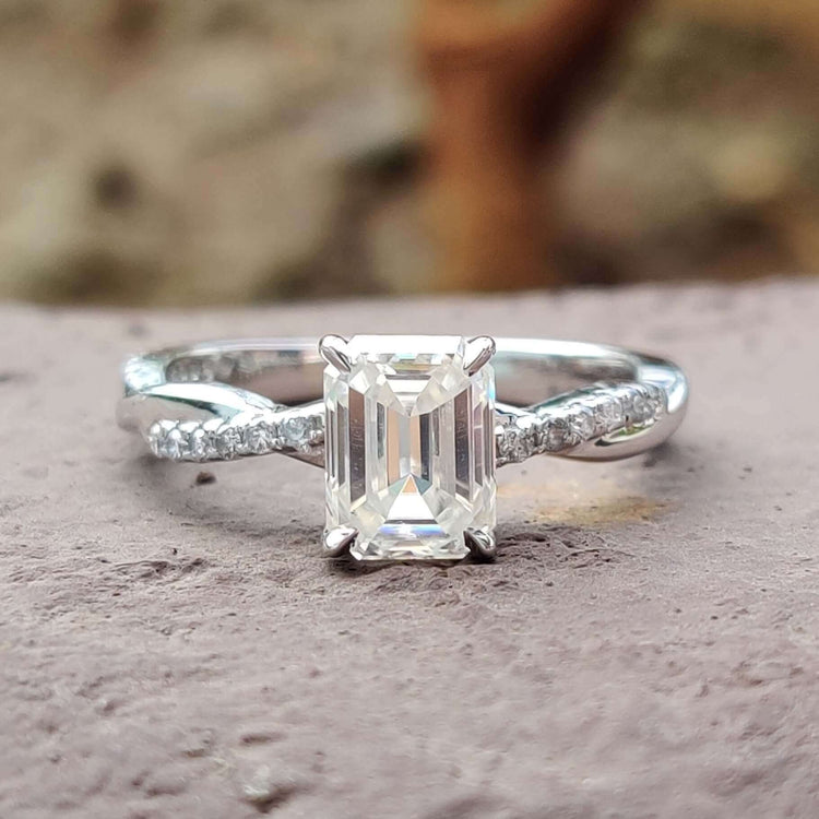 Emerald cut moissanite engagement ring with twisted pave band.