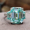 Emerald cut cyan blue moissanite ring in three stone design.