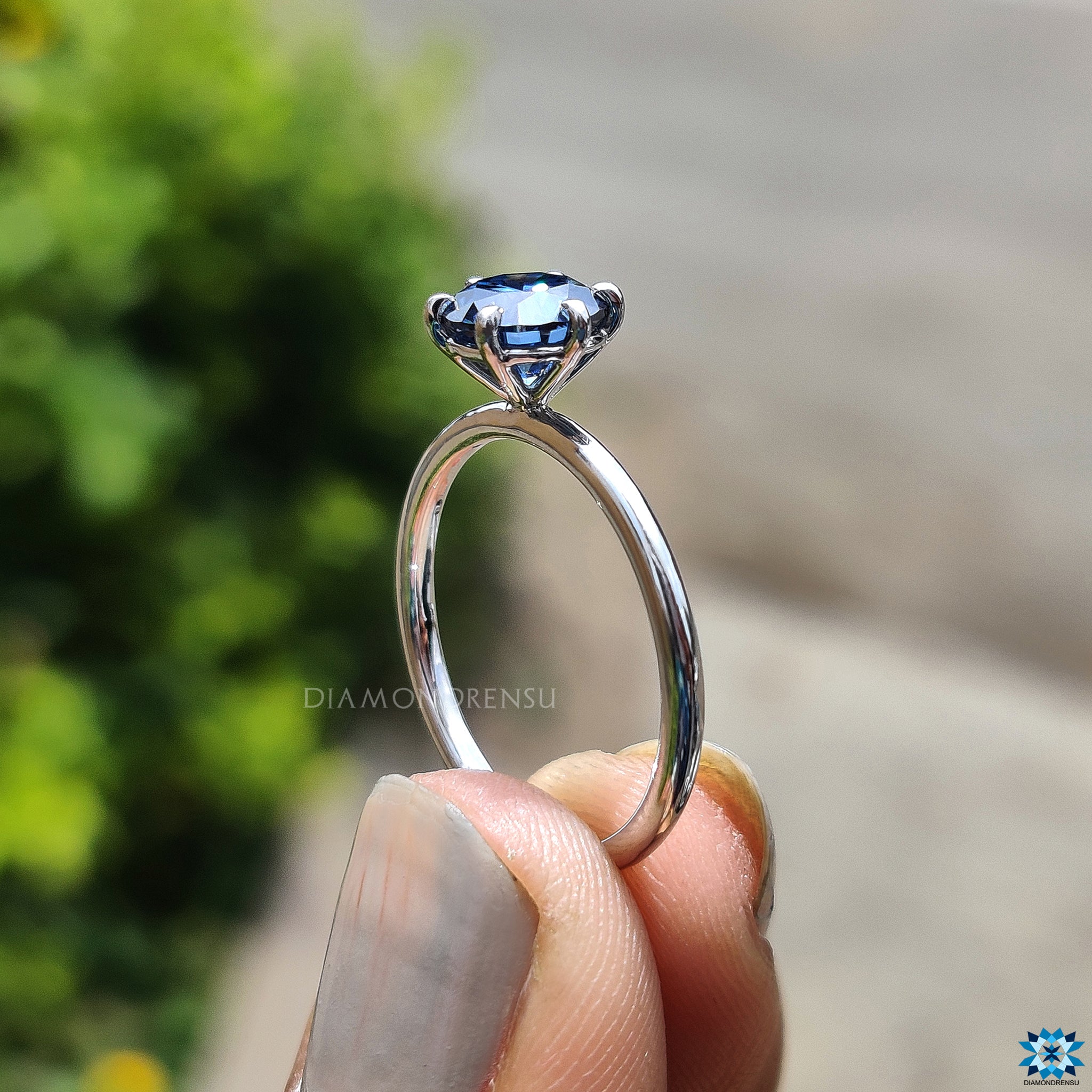 Custom engagement ring crafted with a round cut blue moissanite centre.