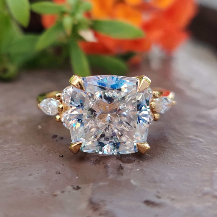 Cushion moissanite ring in muse setting with round and marquise side stones in yellow gold ring.