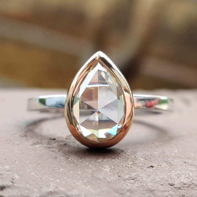 Pear shaped moissanite engagement ring in rose and white gold.