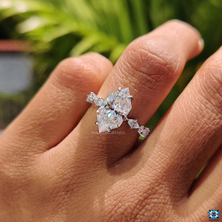 Round cut side moissanite enhances Dutch marquise centre in claw setting.