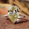 Light yellow pear cut moissanite engagement ring with round side stones.