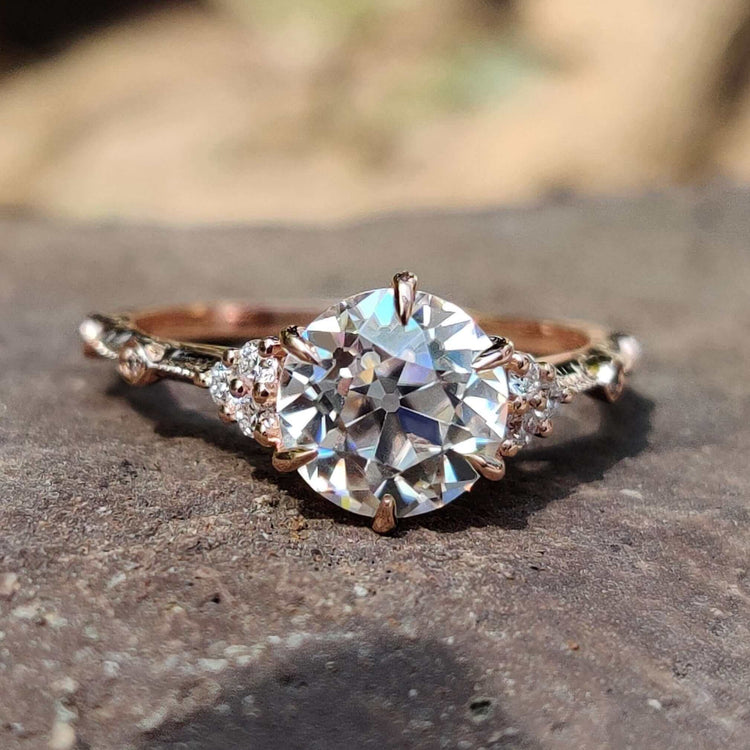 Rose gold moissanite ring with old European cut and round side stones.