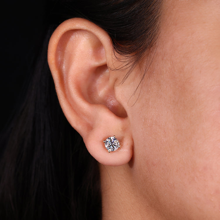 Round diamond earrings crafted as classic gold studs.