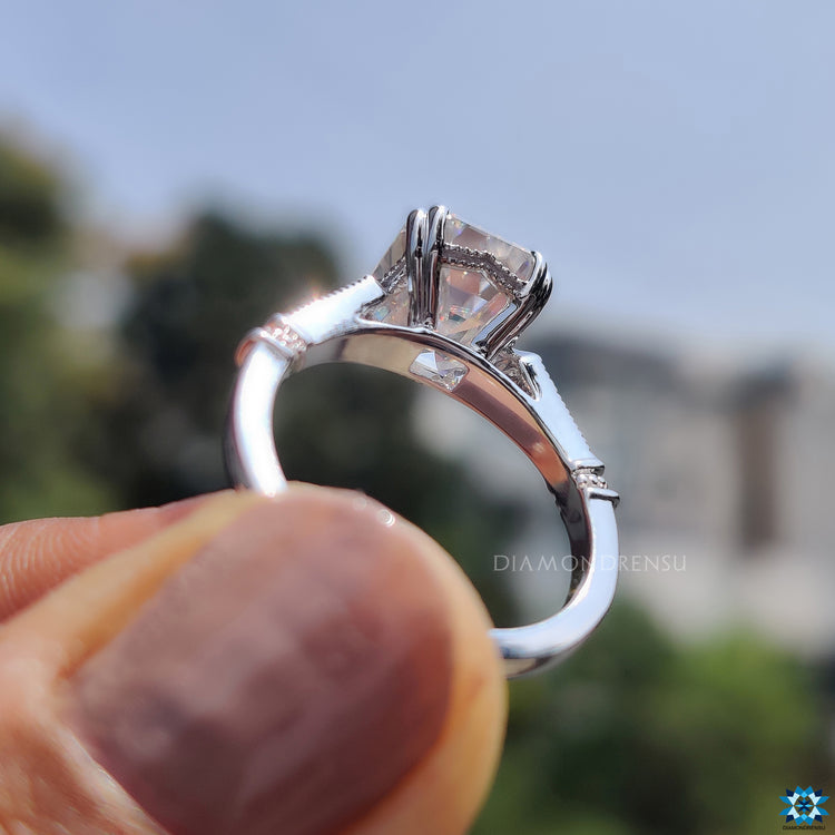 Round side stone ring in white gold with emerald cut centre.