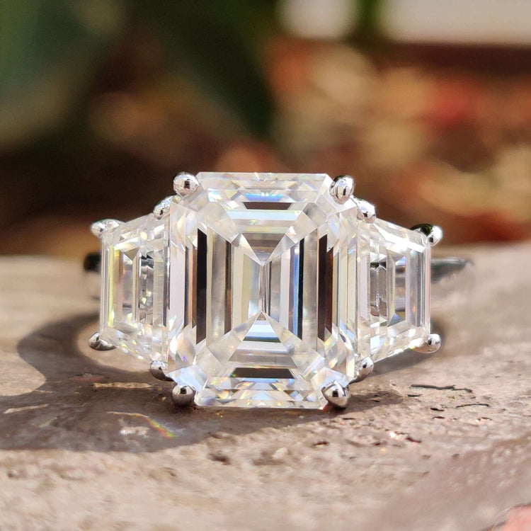Three stone ring with emerald centre and trapezoid side stones.