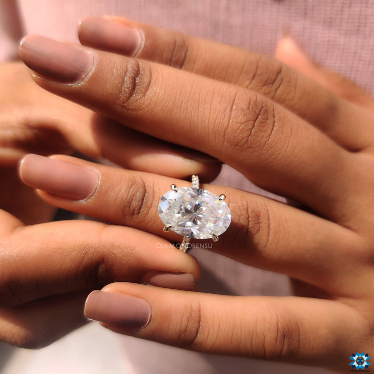 UK engagement ring with yellow gold band and oval moissanite in hidden halo setting.