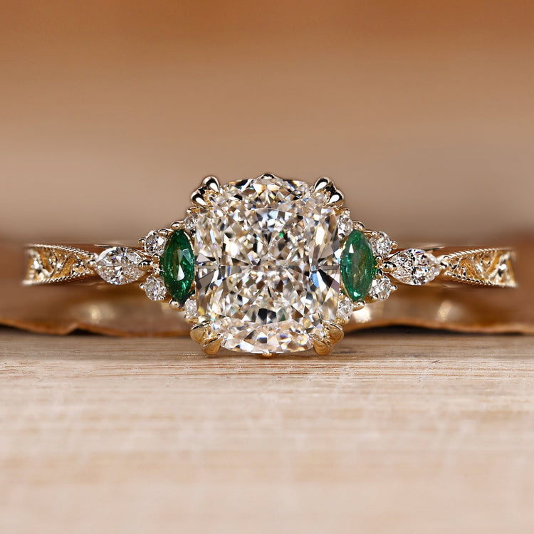 Cushion cut diamond ring with marquise green emerald side stone.
