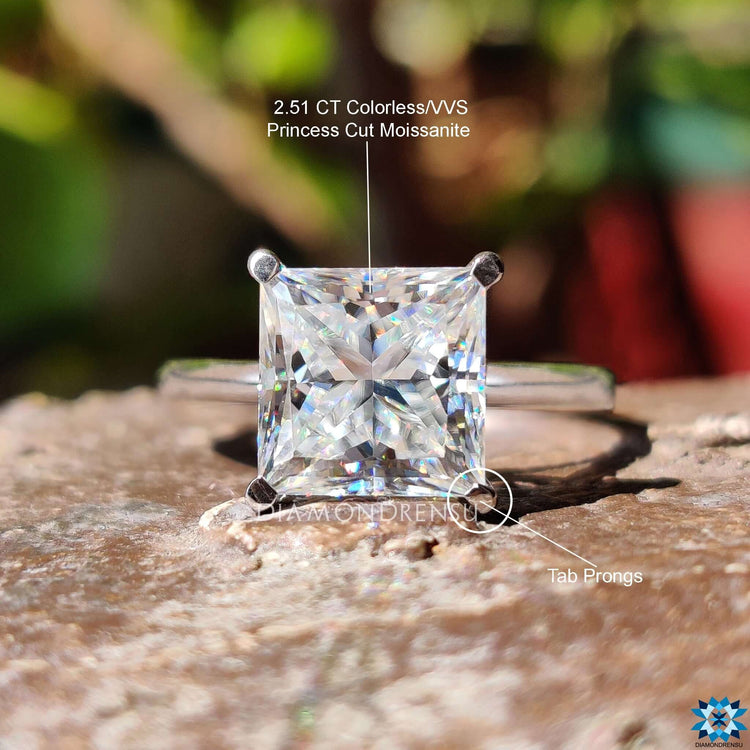 Moissanite engagement ring with a cathedral shank and precision-set princess cut center.