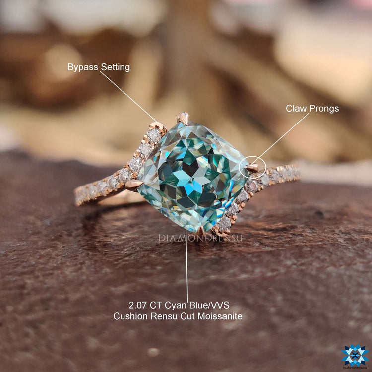 Bypass setting ring with cyan blue cushion moissanite and round cuts.