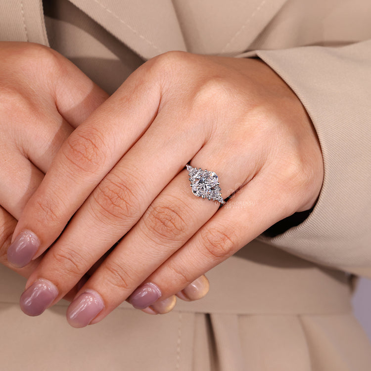 Oval cut diamond ring with tapered shank and cluster setting.