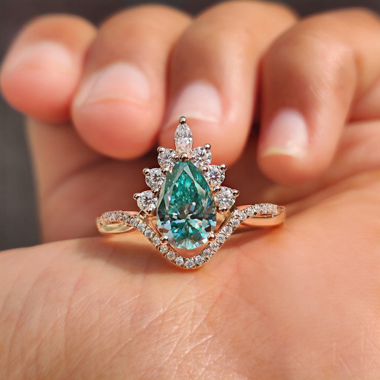 Halo engagement ring with pear cut cyan blue Moissanite.