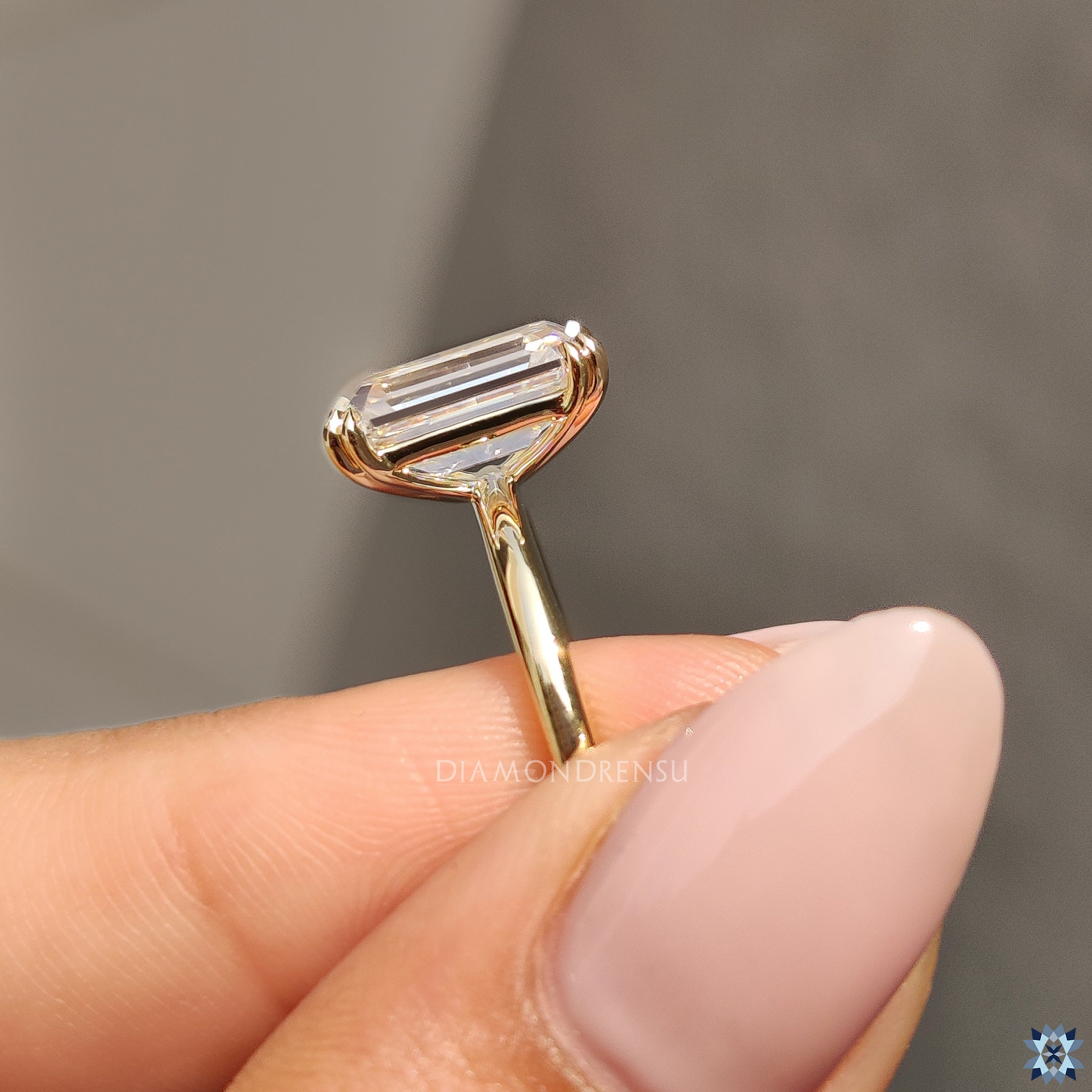 Custom engagement ring with solitaire emerald moissanite and claw prong setting.