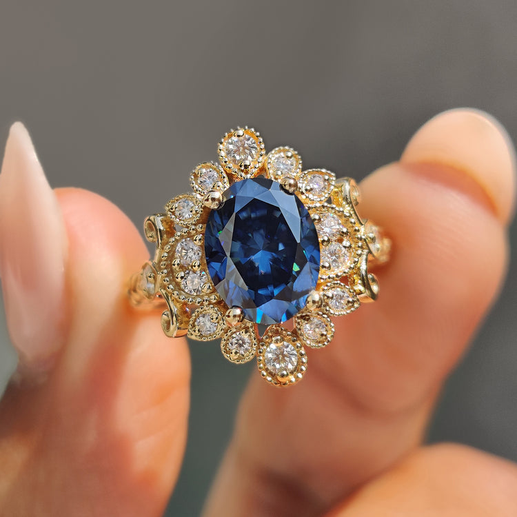 Oval moissanite engagement ring in yellow gold with milgrain detailing.