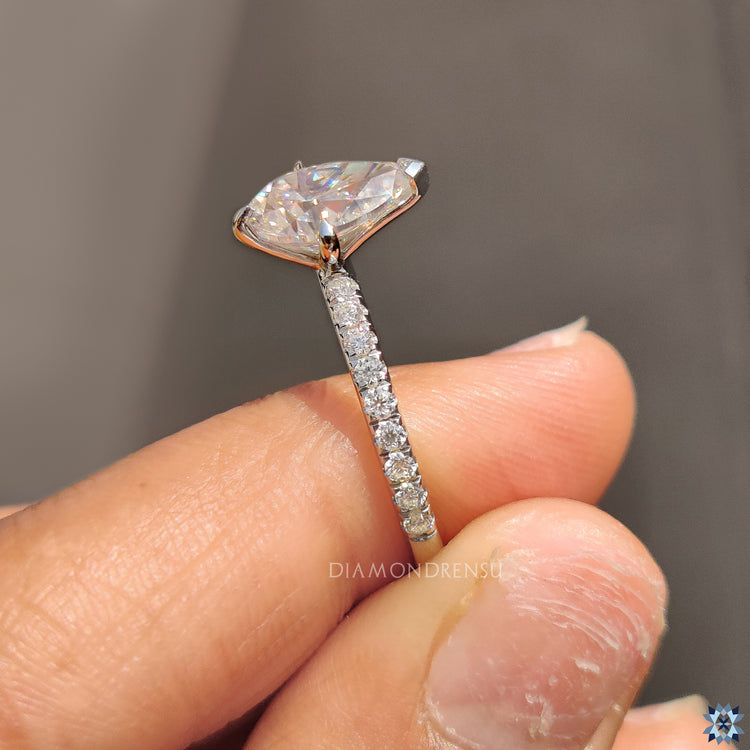 V shaped prong setting ring with pear moissanite and pave band.