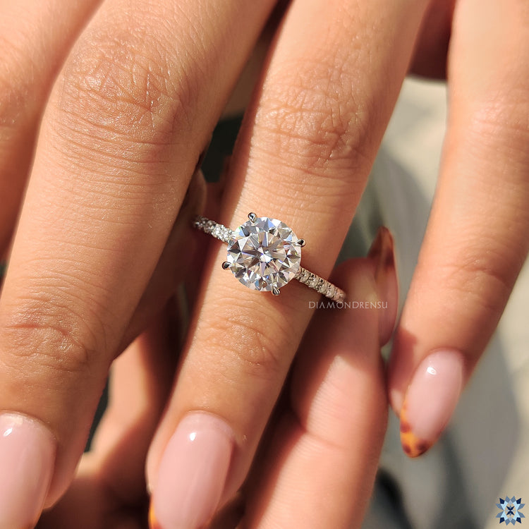 4 claw prong ring showcasing round moissanite and pave details.
