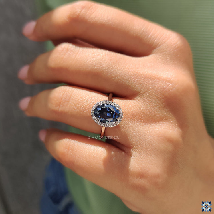UK engagement ring with oval blue stone, halo setting, and elegant cathedral design.