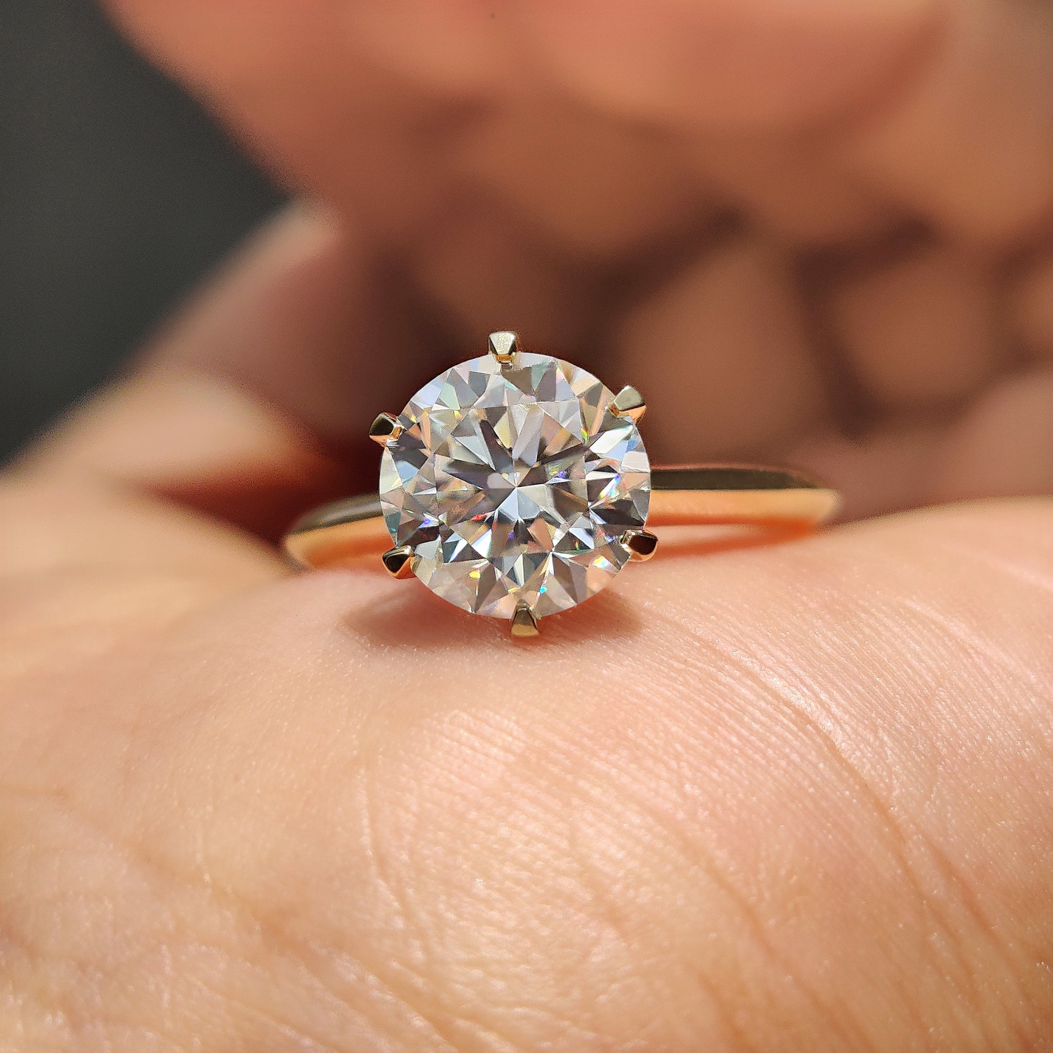 Moissanite solitaire ring with round cut stone and knife edge shank in yellow gold.